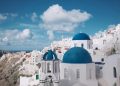 Breathtaking view of Oia's iconic blue-domed churches against a vibrant sky in Santorini, Greece.