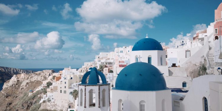 Breathtaking view of Oia's iconic blue-domed churches against a vibrant sky in Santorini, Greece.