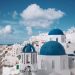 Breathtaking view of Oia's iconic blue-domed churches against a vibrant sky in Santorini, Greece.