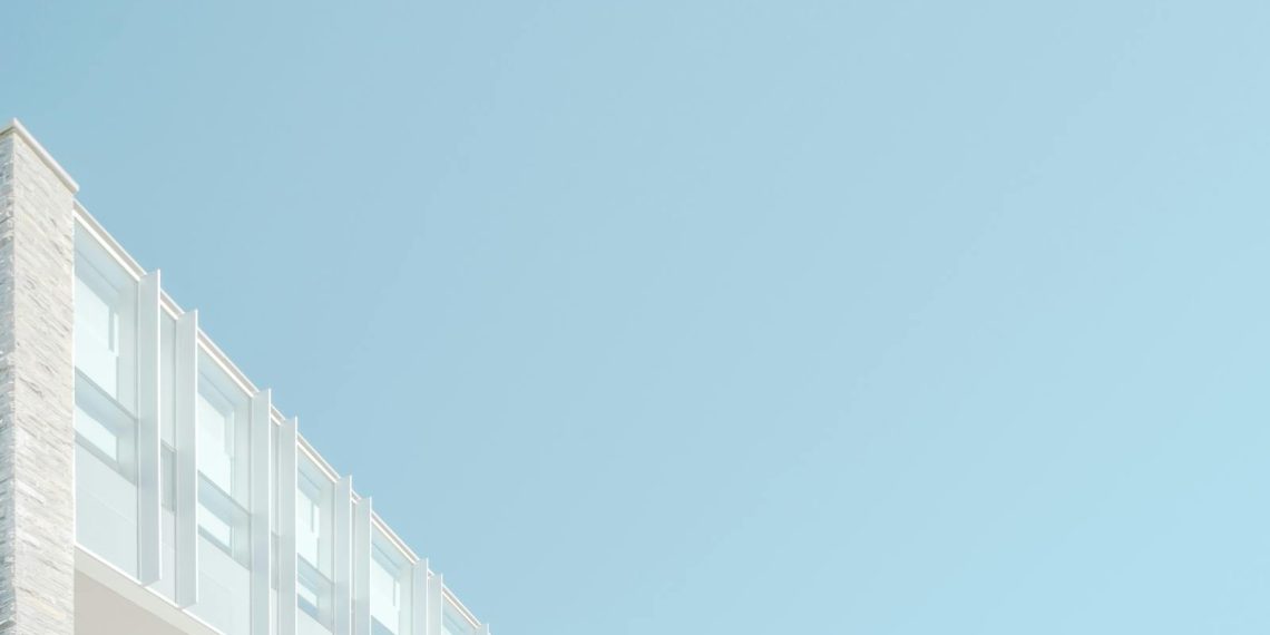 Low angle view of a modern building facade against a blue sky in London, Ontario.