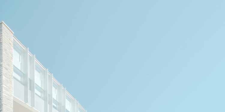 Low angle view of a modern building facade against a blue sky in London, Ontario.