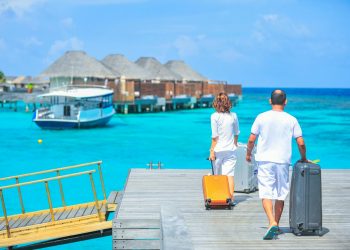 A couple arriving at a luxurious Maldives resort dock with luggage, capturing a tropical vacation vibe.