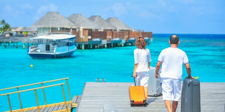 A couple arriving at a luxurious Maldives resort dock with luggage, capturing a tropical vacation vibe.