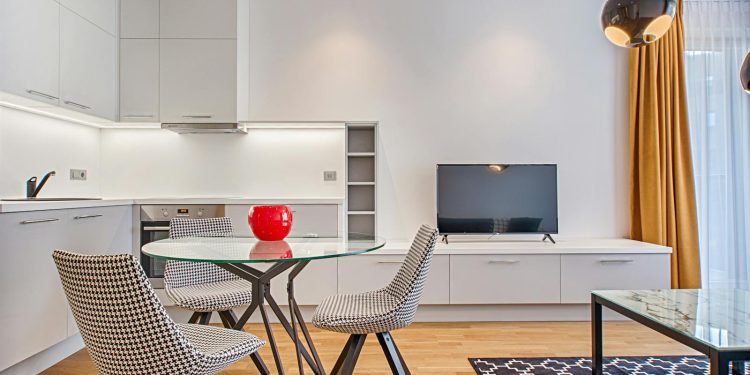 Sleek modern living room with houndstooth chairs, wooden floor, and a glass table.
