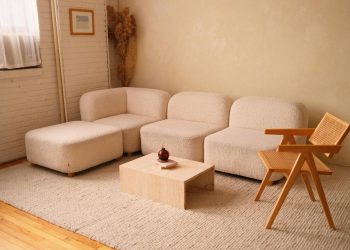 A cozy minimalist living room featuring a plush sofa and contemporary wooden chair.