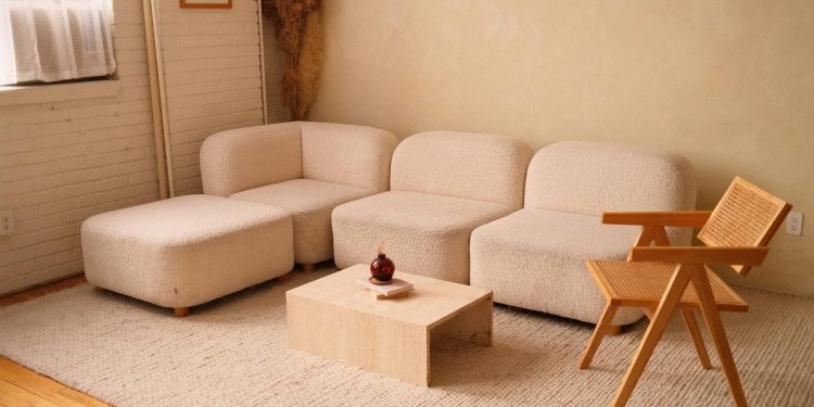 A cozy minimalist living room featuring a plush sofa and contemporary wooden chair.