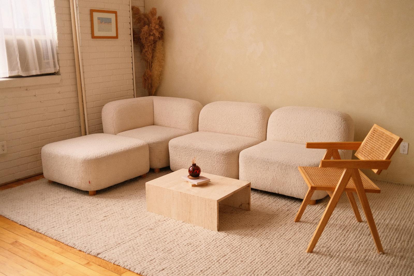 A cozy minimalist living room featuring a plush sofa and contemporary wooden chair.