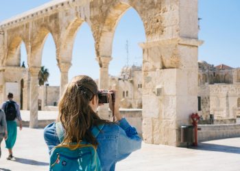 A tourist photographs the ancient stone arches in Jerusalem's Old Town, capturing the essence of travel and history.
