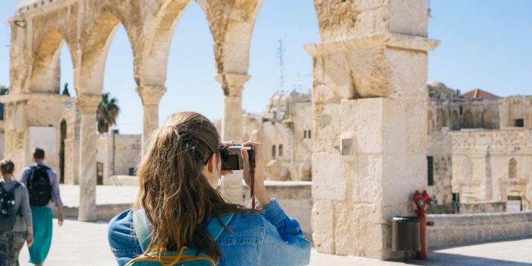 A tourist photographs the ancient stone arches in Jerusalem's Old Town, capturing the essence of travel and history.