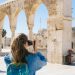 A tourist photographs the ancient stone arches in Jerusalem's Old Town, capturing the essence of travel and history.