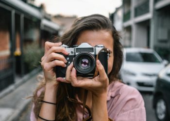 A woman captures a street scene with a classic camera in Surry Hills, Australia.