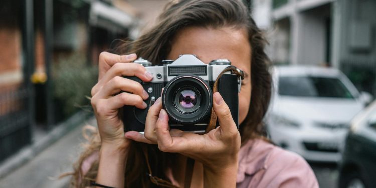 A woman captures a street scene with a classic camera in Surry Hills, Australia.