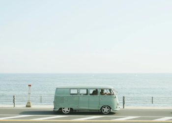 A classic Volkswagen van driving on a seaside road in Fujisawa, Japan, capturing a nostalgic coastal vibe.