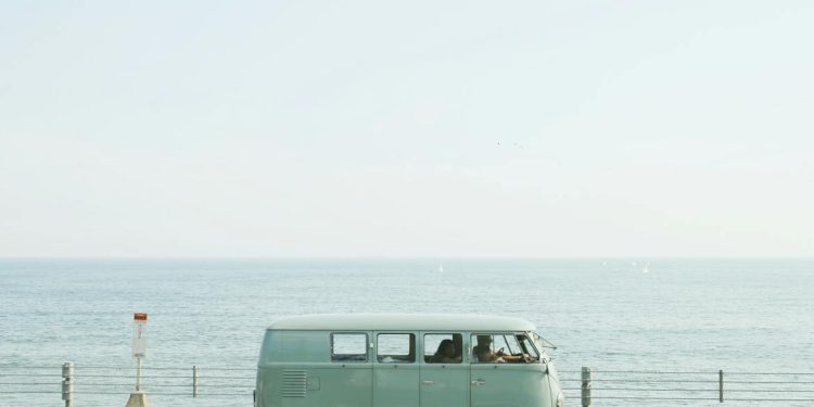 A classic Volkswagen van driving on a seaside road in Fujisawa, Japan, capturing a nostalgic coastal vibe.