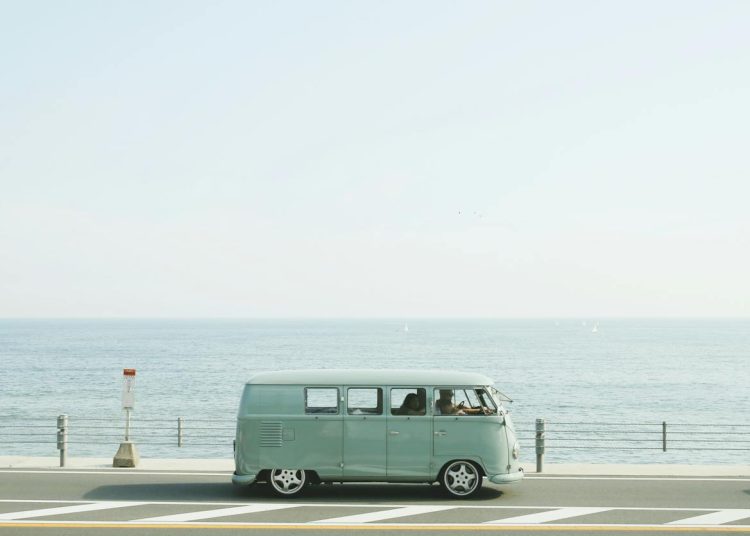 A classic Volkswagen van driving on a seaside road in Fujisawa, Japan, capturing a nostalgic coastal vibe.