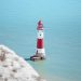 white and red lighthouse on rock formation beside body of water during daytime