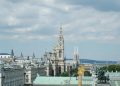 A beautiful view of Vienna's iconic architecture including the Rathaus and Votivkirche under a cloudy sky.