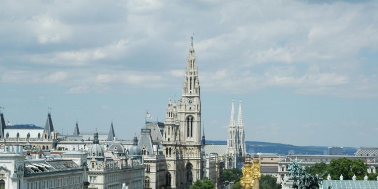 A beautiful view of Vienna's iconic architecture including the Rathaus and Votivkirche under a cloudy sky.