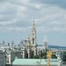 A beautiful view of Vienna's iconic architecture including the Rathaus and Votivkirche under a cloudy sky.
