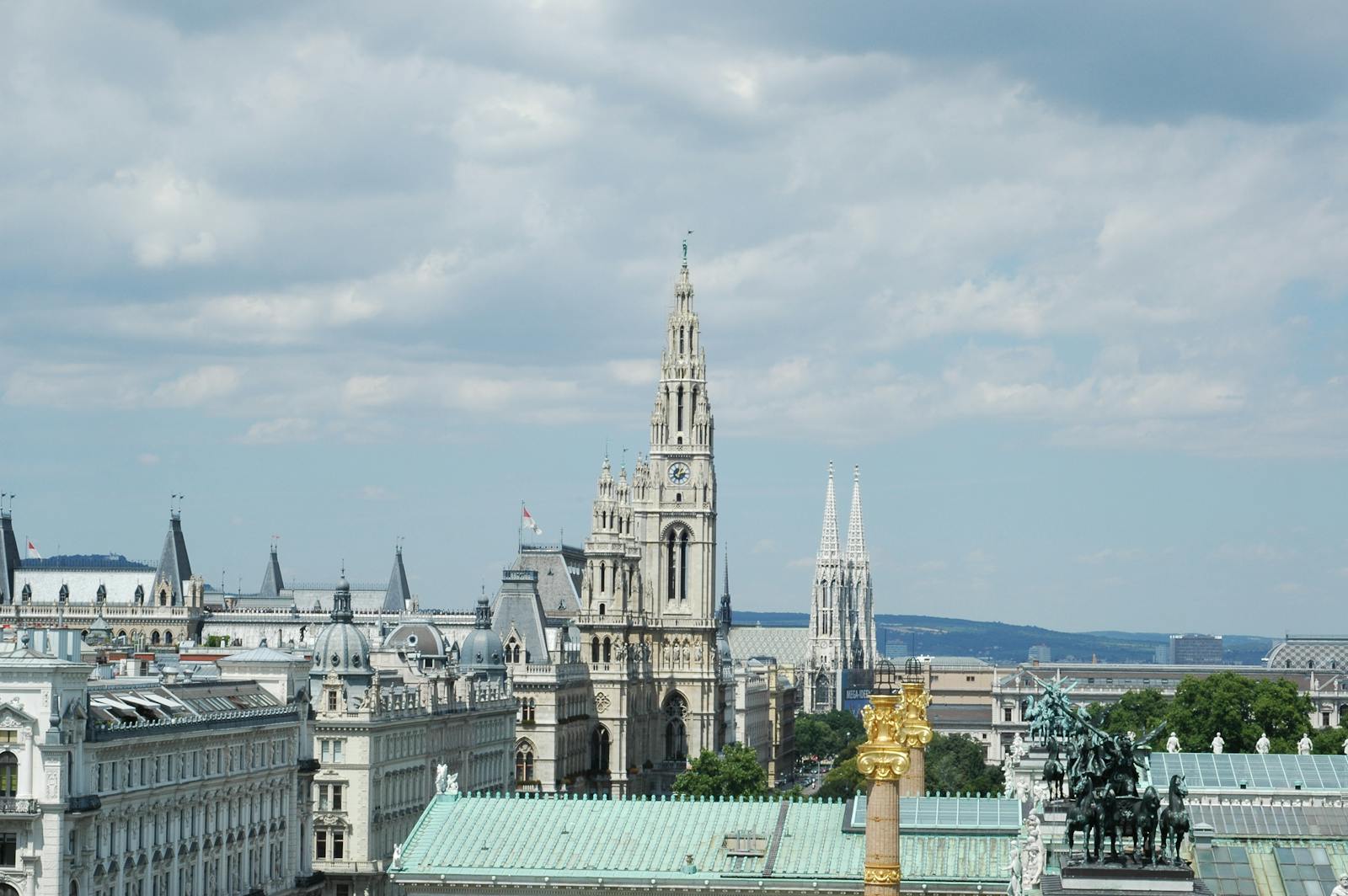 A beautiful view of Vienna's iconic architecture including the Rathaus and Votivkirche under a cloudy sky.