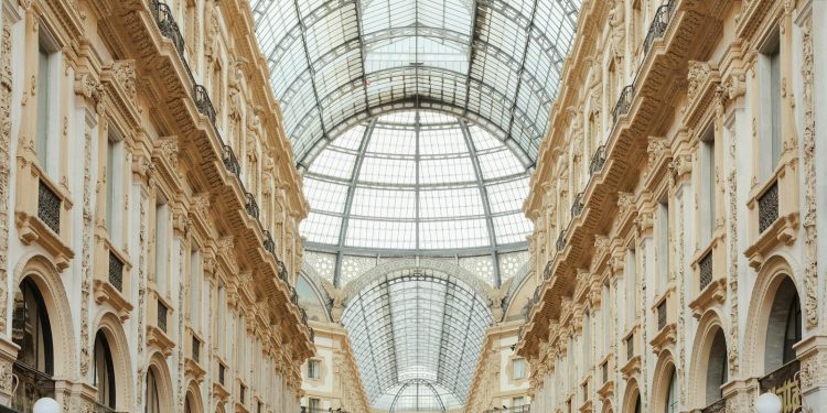 Beautiful view of Galleria Vittorio Emanuele II's interior glass roof and intricate facade in Milan, Italy.