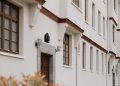 Classic white residential building exterior with brown accents and green foliage.