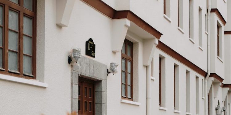 Classic white residential building exterior with brown accents and green foliage.