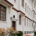 Classic white residential building exterior with brown accents and green foliage.