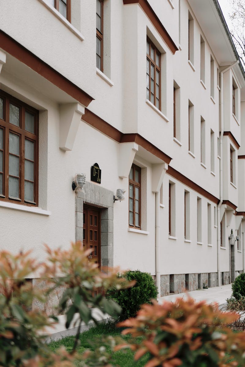 Classic white residential building exterior with brown accents and green foliage.