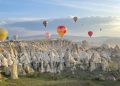 Breathtaking view of hot air balloons floating over Cappadocia's fairy chimneys at sunrise.