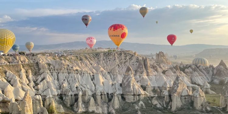 Breathtaking view of hot air balloons floating over Cappadocia's fairy chimneys at sunrise.