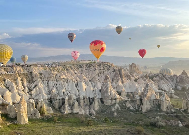 Breathtaking view of hot air balloons floating over Cappadocia's fairy chimneys at sunrise.