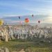 Breathtaking view of hot air balloons floating over Cappadocia's fairy chimneys at sunrise.