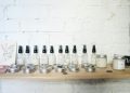Minimalist skincare products displayed on a wooden shelf against a white brick wall.