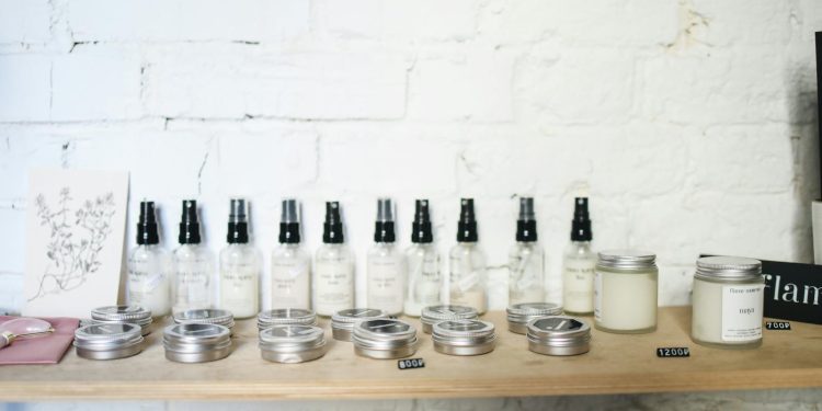 Minimalist skincare products displayed on a wooden shelf against a white brick wall.