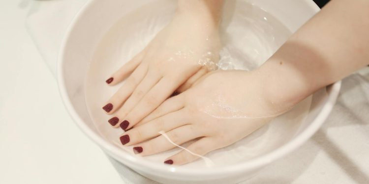 Luxurious hand spa treatment with elegant manicured nails submerged in a soothing soak.