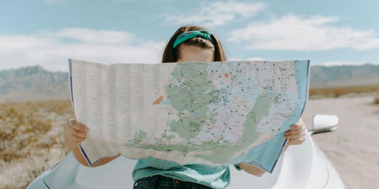 A woman holds a map while traveling through the scenic desert of California, USA.