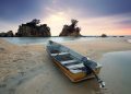 A peaceful seashore scene featuring a fishing boat on sand with a stunning dusk sky.