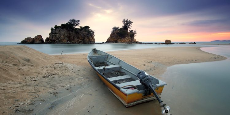 A peaceful seashore scene featuring a fishing boat on sand with a stunning dusk sky.