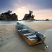 A peaceful seashore scene featuring a fishing boat on sand with a stunning dusk sky.