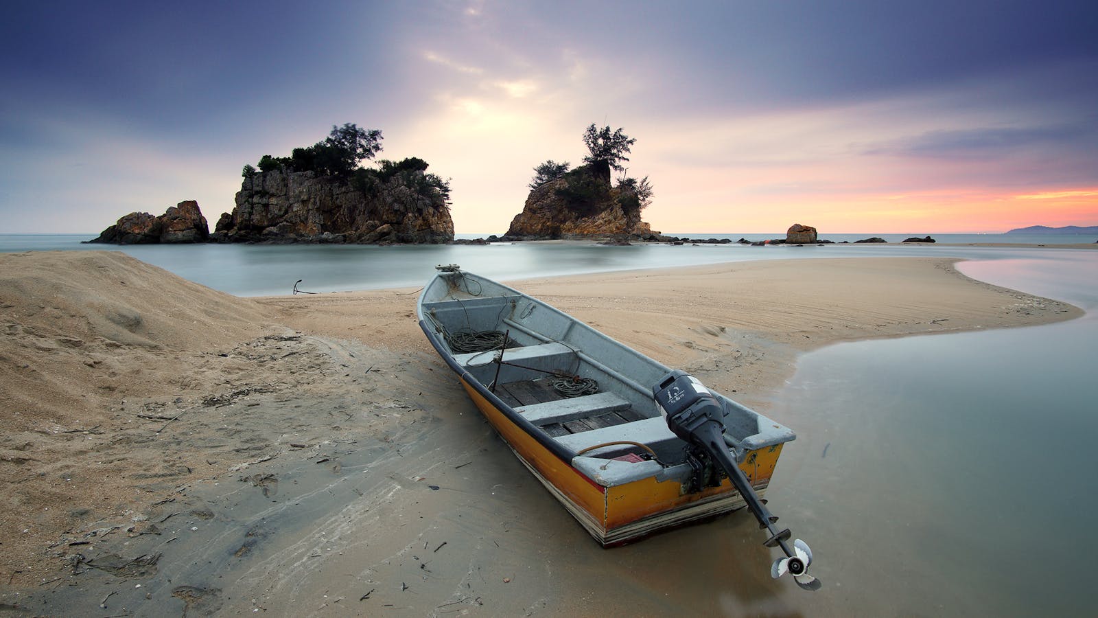 A peaceful seashore scene featuring a fishing boat on sand with a stunning dusk sky.