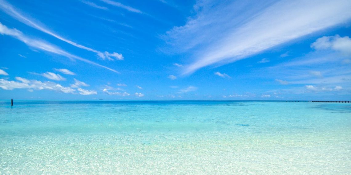 Experience the tranquil turquoise waters and clear sky at Laamu Atoll, Maldives. Perfect for a relaxing getaway.