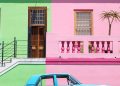 blue sedan parked beside pink and green house