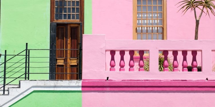 blue sedan parked beside pink and green house