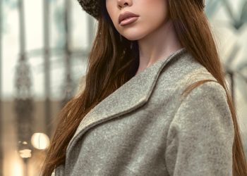 a woman in a coat and hat poses for a picture