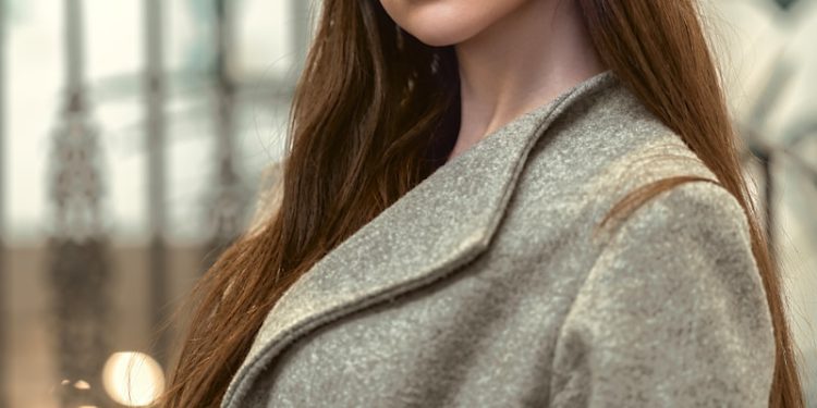 a woman in a coat and hat poses for a picture