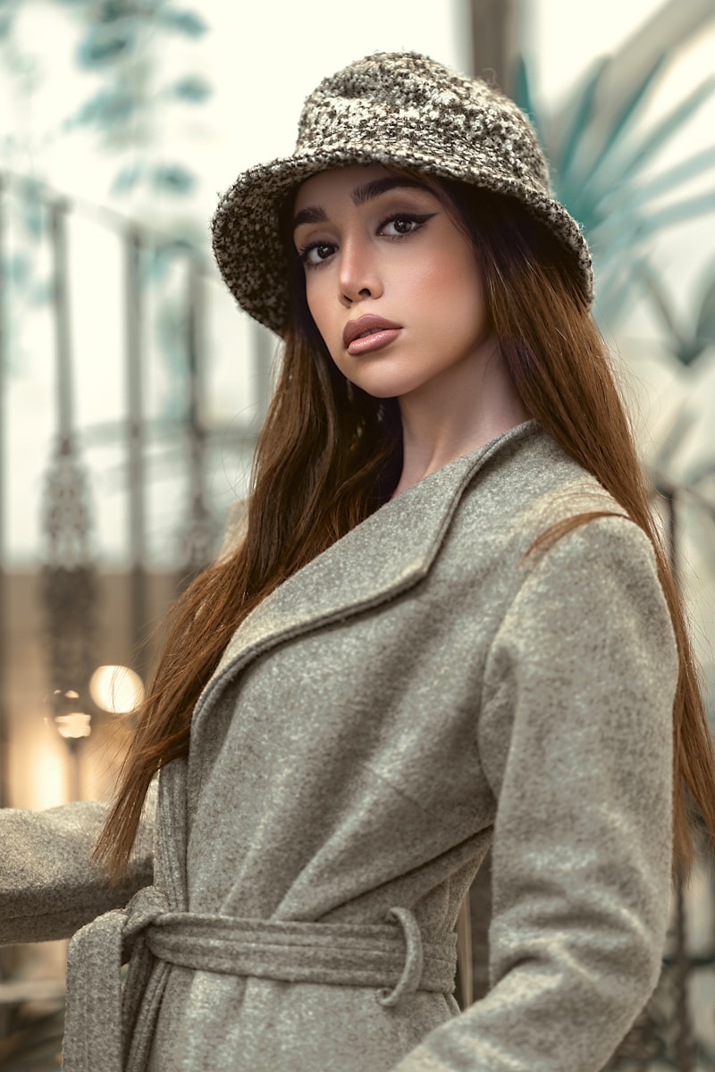 a woman in a coat and hat poses for a picture