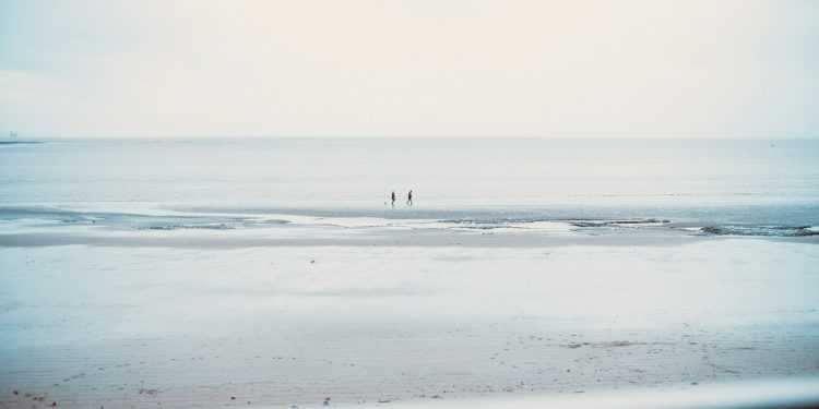 two people standing on a beach near the ocean