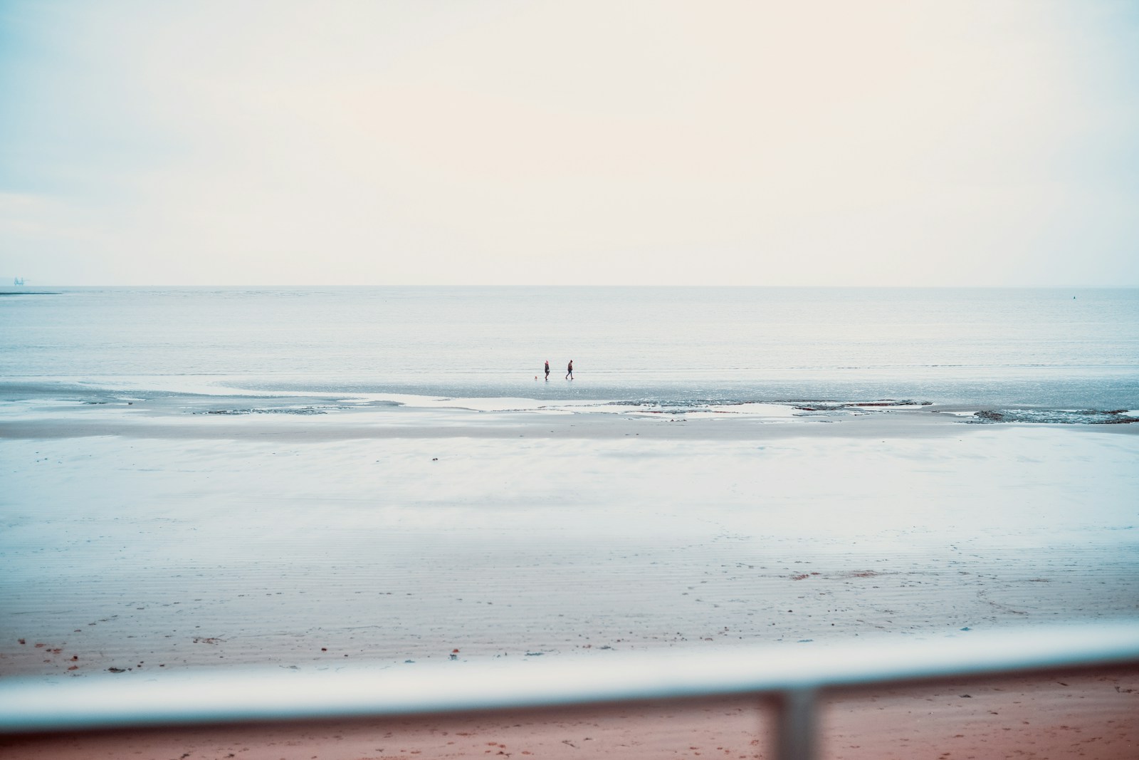 two people standing on a beach near the ocean